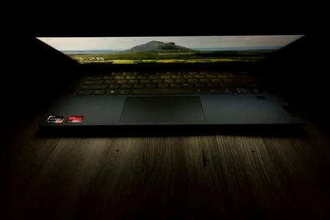 Laptop computer screen lighting up a dark desk Stock Photos