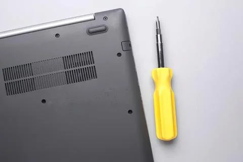Laptop computer with screwdriver tool on light background 스톡 사진