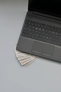 Laptop computer with stack of hundred dollar bills. Online earnings concept. 库存照片