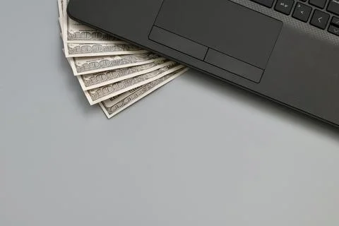 Laptop computer with stack of hundred dollar bills. Online earnings concept. Stock Photos