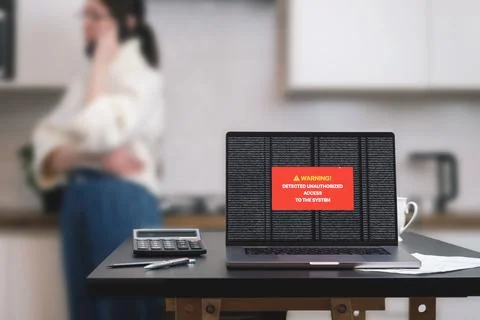 A laptop computer standing on a table with a system hacking message on the .. Stock Photos