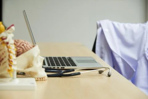 Laptop computer, stethoscope, human brain and spine model on the desk Stock Photos