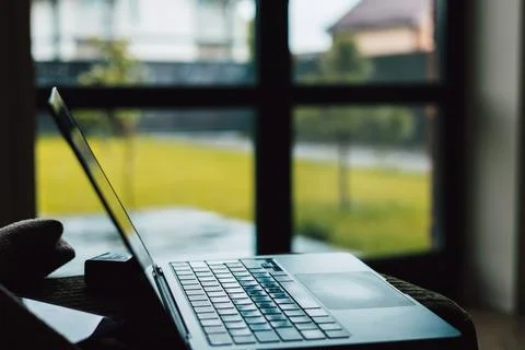 A laptop computer on a table beside a large window at home Stock Photos