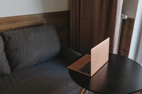 Laptop computer on table near comfortable sofa Stock Photos