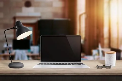 Laptop computer on table in office with brick walls. Window and sunlight in b Stock Photos
