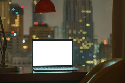 Laptop computer on table white display see through city on night Stock Photos