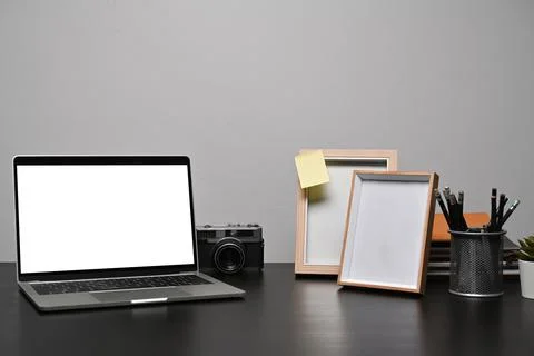 Laptop computer with white screen, camera and empty picture frames on black Stock Photos