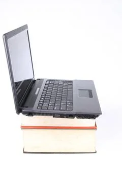 A laptop computers on thick of books evolution from books to computers Cop... Stock Photos