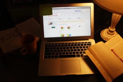 Laptop, diary, pen, sticky notes, book, table lamp and coffee on the work desk Stock-Fotos