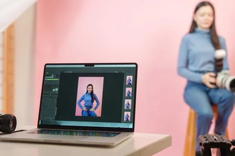 Laptop displaying photo editing software during studio photo session with model Stock Photos