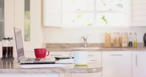 Laptop, documents and mugs of coffee on countertop in kitchen Stock Footage 336896811