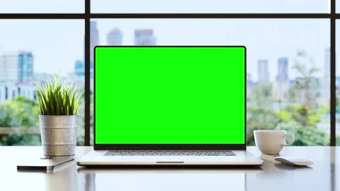 A laptop with an empty green screen on the desk in the office, with trees  .. Stock Footage 243003427
