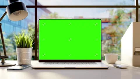 A laptop with an empty green screen on the desk in the office, with trees  .. Stock Footage 243003491