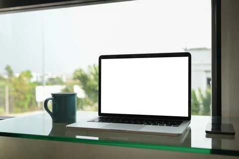 Laptop with empty screen and cup of coffee on table near window. Empty screen Stock Photos