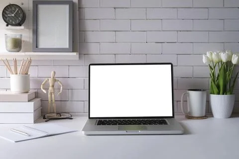 Laptop with empty screen, picture frame, flower pot and supplies on white t.. Stock Photos