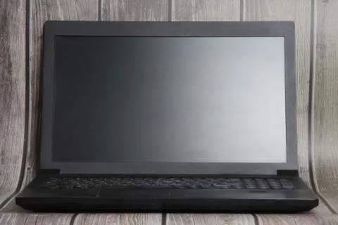 A laptop with a empty screen stands on the background of wooden boards. Place Foto stock