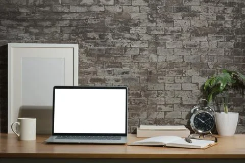 Laptop with empty screen, white empty frame mock up, books and potted plant.. Foto stock