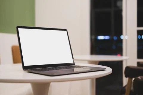 Laptop with empty screen on white round table in modern coffee shop or Stock Photos