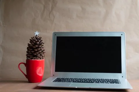 Laptop with empty screen on wooden table, blur Christmas tree and gifts on ba Stock-Fotos