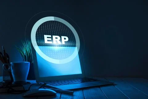 Laptop with ERP software on screen shows digital workspace at night with plants Stock Photos