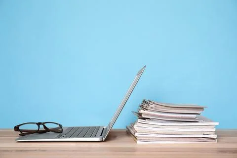 Laptop, glasses and stack of magazines on wooden table Stock Photos