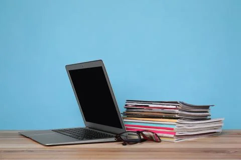 Laptop, glasses and stack of magazines on wooden table Foto stock