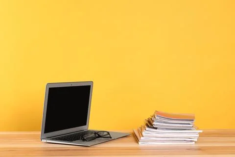 Laptop, glasses and stack of magazines on wooden table. Space for text Stock Photos