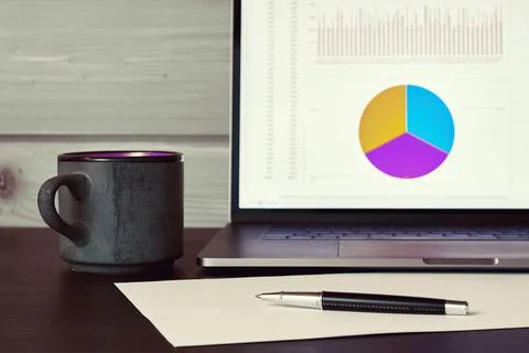 Laptop with graph and datum on the table in the office Stock Photos