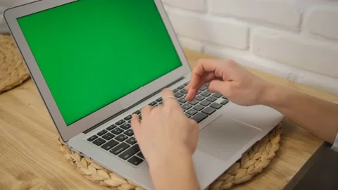 A laptop with a green screen. Close-up of hands working on the keyboard. Remote  Stock Footage 148472147