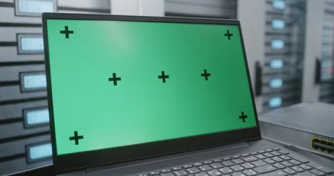 Laptop with Green Screen Display on Table Beside Server Racks in Data Center Stock Footage 344955536