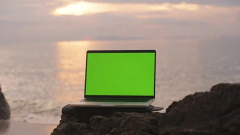 Laptop with Green Screen Placed on Rock by Ocean at Dusk with Sunset Reflection, Stock Footage 317214950