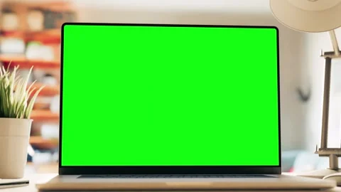 A laptop with a green screen sits on a table in a bright cozy home office. .. 스톡 동영상 278999820