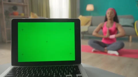 A laptop with a green screen on a table against a blurred background in a room Stock Footage 245397877