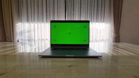 Laptop with the green screen on the table and window closes on the background Stock Footage 146912399