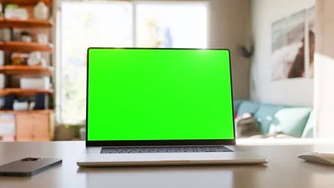 Laptop with a green screen on a table in a bright home office. Perfect for .. Stock Footage 278478150