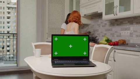 Laptop with a green screen on the table in the kitchen Stock Footage 295814334