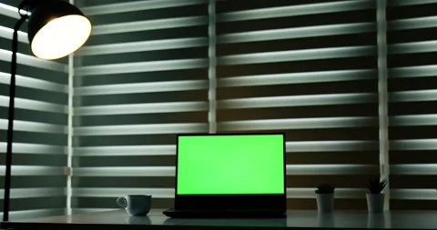 Laptop with green screen on white table in front of roller blind. With Coffee 库存影片 148287987