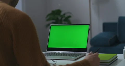 Laptop with green screen on working table in home office view through should 스톡 동영상 279653253
