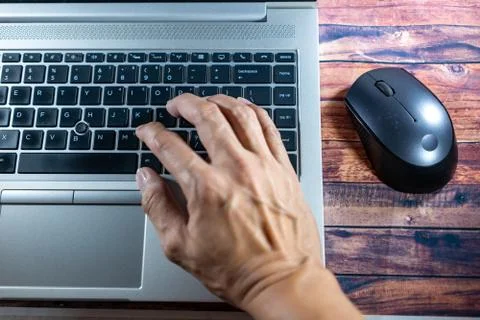 Laptop with a hand while typing or encoding and moving mouse. Business concep Stock Photos