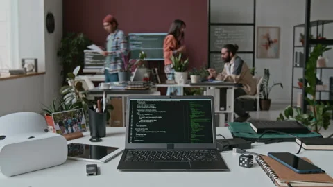 Laptop with Lines of Computer Code on Desk at Busy IT Startup during Workday Stock Footage 285708011