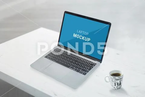 Laptop mockup on white office desk. Cup of coffee beside Modello PSD