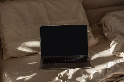Laptop notebook computer sitting on bed in bedroom Stock Photos