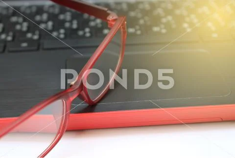 Laptop notebook computer on wood table with eyeglasses with burst light Stock Photos