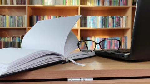 Laptop, notepad and glasses on desk in library Stock Footage 170436503