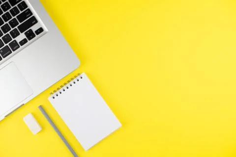 Laptop, notepad planner with gray pencil and erase rubber on yellow backgroun Stock Photos