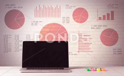 Laptop on office desk with sales pie charts Stock Photos