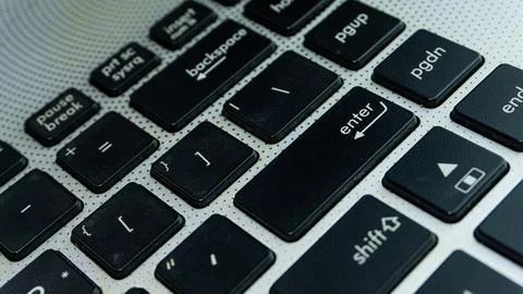 Laptop or computer keyboard with black keys and silver body. Close up focus.. Stock Photos