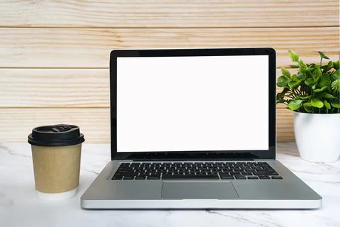 Laptop or notebook with blank screen, coffee and potted plant on white table. Stock Photos