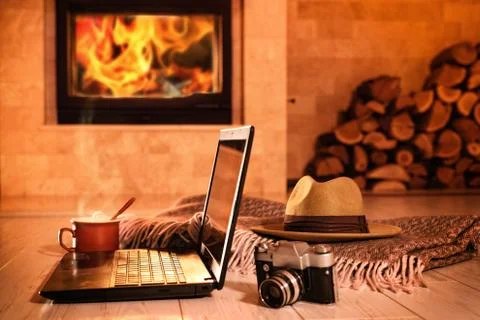 Laptop or notebook, hat, camera, cup on the fireplace background. Foto stock