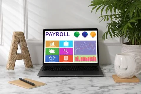 Laptop with payroll data on screen on table Stock Photos
